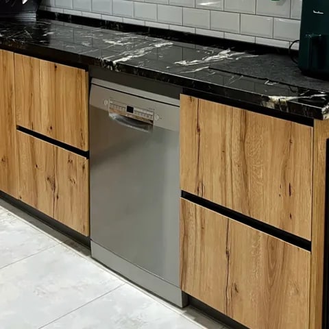 Detalle de carpintería en cocina con frentes en madera natural - David Carpintería Muebles de cocina en madera con tirador integrado y electrodoméstico panelado